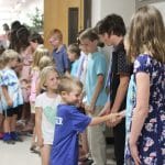 Graduates greet their classmates and teachers with a handshake