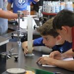 Eighth grade students measuring volume and weight of materials gathered in the playground.