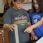 Eighth grade students measuring volume and weight of materials gathered in the playground.