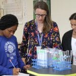 Science teacher Sarah Mitch with eighth grade students measuring volume and weight of materials gathered in the playground.