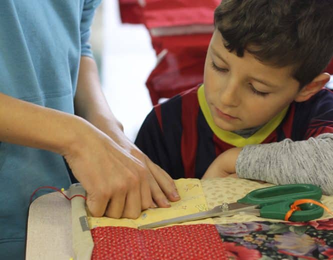 Kindergarten students and eighth graders worked in pairs to knot comforters.