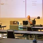 Jesse Blosser prepares Algebra II on day 1 to teach in the Commons, tables spread far and set with an EMS mask for everyone.