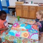 Title: Rainbow Rocket
Size: 24”x18”
Medium: acrylic paint
Description: Kindergarten artists worked in small groups to paint abstract designs directly on a cradled wooden panel. Beginning at the edges and working inward they painted large patches of color as a base layer. Additional layers were created using small blocks of color along with line, shape, and pattern designs. Students were thoughtful in selecting colors that would stand out next to each other, and  they enjoyed talking together about their painting. As the final step in their creative process, the class brainstormed title ideas for their piece then voted for their favorite.
