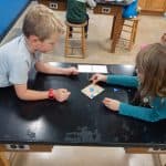 Title: The Colorful Ghosts
Size: 24”x18”
Media: acrylic paint
Description: 1st grade artists used printmaking to create a colorful quilt-like composition. Each student rolled paint onto a rectangular piece of foam and stamped the shape onto the wooden panel. After designing a printmaking block with foam shapes, they rolled paint onto it and stamped it directly over their solid block of color. Students repeated this process with a partner to create a second print. These student pairs practiced sharing their ideas for design and color choices. The last printed block was created by the entire class. As the final step in their creative process, the class brainstormed title ideas for their piece then voted for their favorite.
