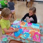Title: Rainbow Rocket
Size: 24”x18”
Medium: acrylic paint
Description: Kindergarten artists worked in small groups to paint abstract designs directly on a cradled wooden panel. Beginning at the edges and working inward they painted large patches of color as a base layer. Additional layers were created using small blocks of color along with line, shape, and pattern designs. Students were thoughtful in selecting colors that would stand out next to each other, and  they enjoyed talking together about their painting. As the final step in their creative process, the class brainstormed title ideas for their piece then voted for their favorite.
