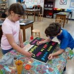 Title: Cozy Fire
Size: 24”x18”
Medium: acrylic paint
Description: 4th grade artists brainstormed and voted on an inspirational saying to serve as the centerpiece of their painting. Next, they collaborated to determine the color scheme and design. This was an important exercise in both sharing and listening respectfully. Students worked in small groups to draw and paint the composition. As the final step in their creative process, the class brainstormed title ideas for their piece then voted for their favorite.
