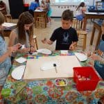Title: Rainbow Shadows
Size: 24”x18”
Media: paper, acrylic paint
Description: 3rd grade artists each painted four 4x4 squares of paper a solid background color (chosen from the project color scheme), then used a variety of tools such as spools, wooden blocks, and lids to create patterns and implied textures. The large squares were cut into a series of squares and rectangles. Students adhered their individual pieces onto a cradled wooden panel, intermingled with those of their classmates, arranging them into a quilt pattern. As the final step in their creative process, the class brainstormed title ideas for their piece then voted for their favorite.
