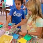 Title: Rainbow Shadows
Size: 24”x18”
Media: paper, acrylic paint
Description: 3rd grade artists each painted four 4x4 squares of paper a solid background color (chosen from the project color scheme), then used a variety of tools such as spools, wooden blocks, and lids to create patterns and implied textures. The large squares were cut into a series of squares and rectangles. Students adhered their individual pieces onto a cradled wooden panel, intermingled with those of their classmates, arranging them into a quilt pattern. As the final step in their creative process, the class brainstormed title ideas for their piece then voted for their favorite.
