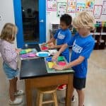Title: Rainbow Shadows
Size: 24”x18”
Media: paper, acrylic paint
Description: 3rd grade artists each painted four 4x4 squares of paper a solid background color (chosen from the project color scheme), then used a variety of tools such as spools, wooden blocks, and lids to create patterns and implied textures. The large squares were cut into a series of squares and rectangles. Students adhered their individual pieces onto a cradled wooden panel, intermingled with those of their classmates, arranging them into a quilt pattern. As the final step in their creative process, the class brainstormed title ideas for their piece then voted for their favorite.

