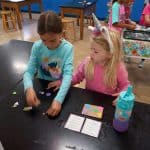 Title: The Colorful Ghosts
Size: 24”x18”
Media: acrylic paint
Description: 1st grade artists used printmaking to create a colorful quilt-like composition. Each student rolled paint onto a rectangular piece of foam and stamped the shape onto the wooden panel. After designing a printmaking block with foam shapes, they rolled paint onto it and stamped it directly over their solid block of color. Students repeated this process with a partner to create a second print. These student pairs practiced sharing their ideas for design and color choices. The last printed block was created by the entire class. As the final step in their creative process, the class brainstormed title ideas for their piece then voted for their favorite.
